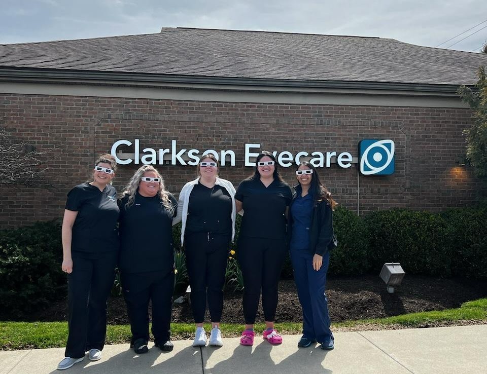 Clarkson Eyecare eye care center in Marysville, OH team of eye care experts standing in front of Clarkson Eyecare outside sign logo smiling group photo